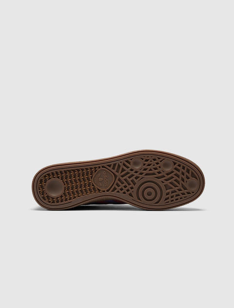 Brown adidas sneaker outsole with textured grip and logo, photographed on a white background