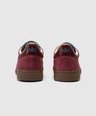 Red and purple suede sneakers with blue logo, gum sole, viewed from the back on white background