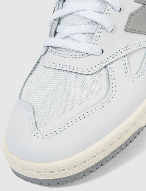 Close-up of white and grey sneaker with mesh and leather materials, detailed stitching, and laces.