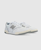 White and grey low-top sneakers with lace-up design and side logo on a light background