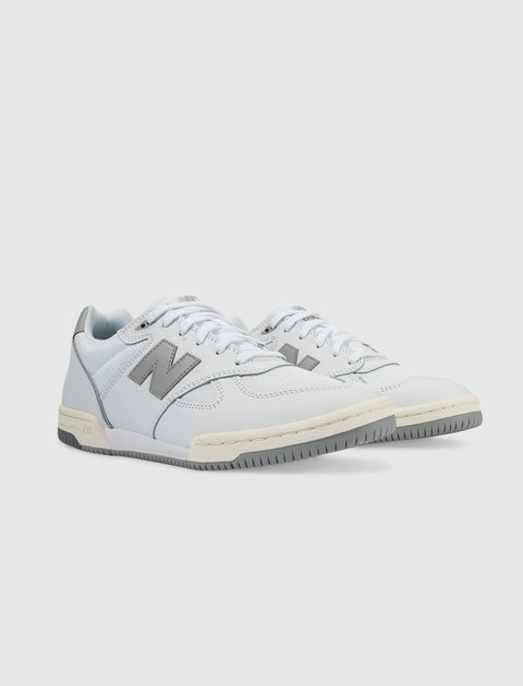 White and grey low-top sneakers with lace-up design and side logo on a light background