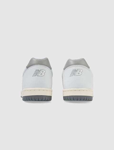 Rear view of white and grey low-top sneakers with logo on heel, grey outsoles