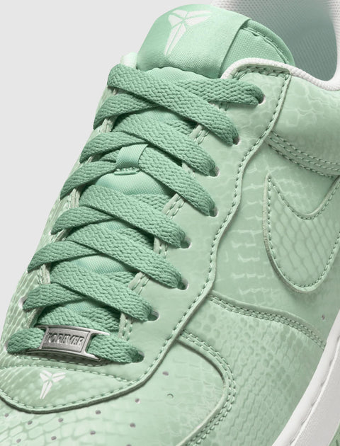 Mint green low-top sneaker with snakeskin texture, white sole, and signature logo details.