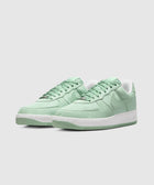 Light green low-top sneakers with textured leather and white sole on gray background