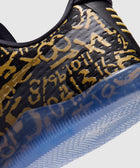 Close-up of black sneaker with gold graffiti-style text and translucent blue sole