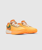 Orange and green low-top sneakers with white laces on a plain gray background