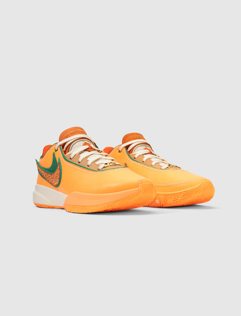 Orange and green low-top sneakers with white laces on a plain gray background