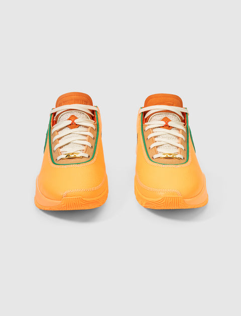 Orange and green low-top sneakers with cream laces, front view on white background