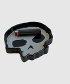 Black skull-shaped ashtray with lighter on gray background