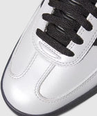 Close-up of silver leather sneaker toe with black laces and stitching details