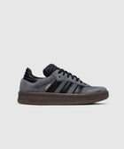 Gray and black suede low-top sneaker with textured brown sole and gold Samba text