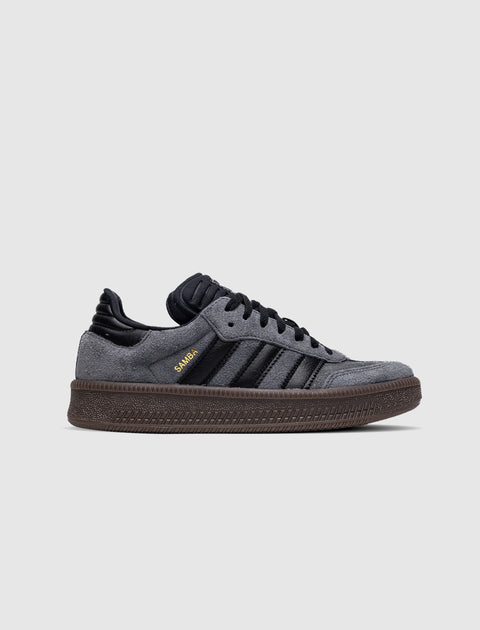 Gray and black suede low-top sneaker with textured brown sole and gold Samba text