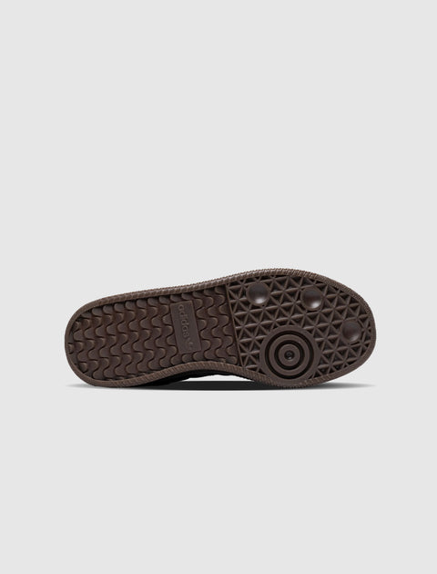 Close-up of black adidas sneaker sole with textured grip and logo on white background