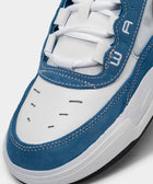 Close-up of a white and blue suede sneaker with white laces and stitched detailing