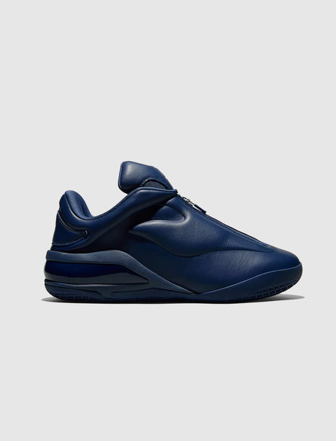 Dark navy blue low-top sneaker with smooth leather upper, side profile on white background