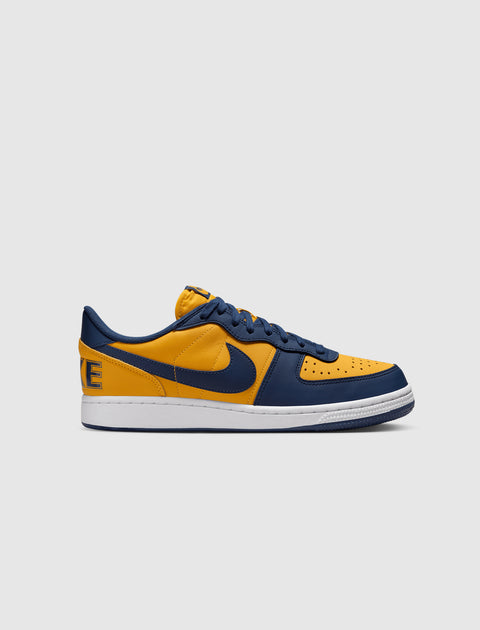 Low-top sneaker in yellow and navy leather with white sole, side profile on plain background