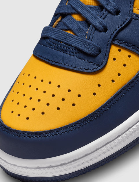 Close-up of a yellow and navy blue leather sneaker with perforated toe box and white sole
