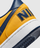 Close-up of yellow and navy low-top sneaker with bold logo on the heel and white sole