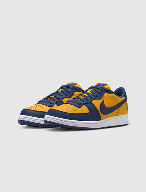 Yellow and navy low-top sneakers with perforated toe and white sole on white background