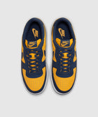 Yellow and navy low-top sneakers with Nike logo, viewed from above on a plain background