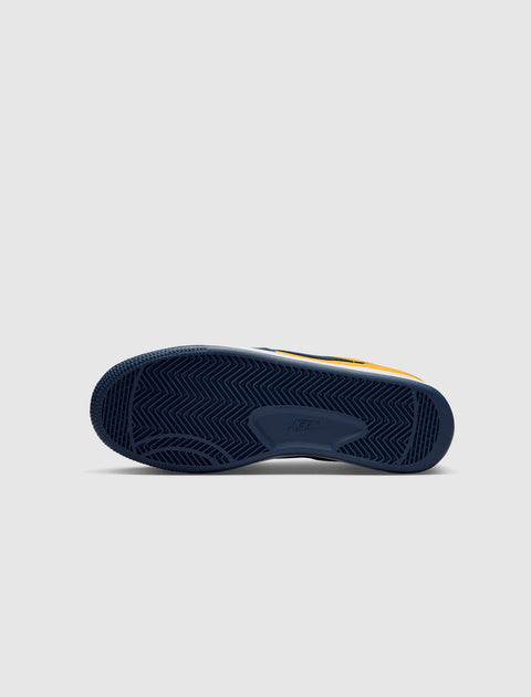 Close-up of navy blue sneaker sole with herringbone tread pattern on light background