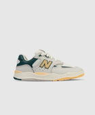 Cream and green low-top sneaker with yellow accents and chunky sole, side profile on white background.