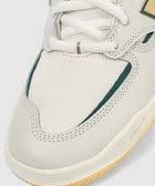 Close-up of white sneaker toe with mesh and suede details, rubber sole, and white laces.