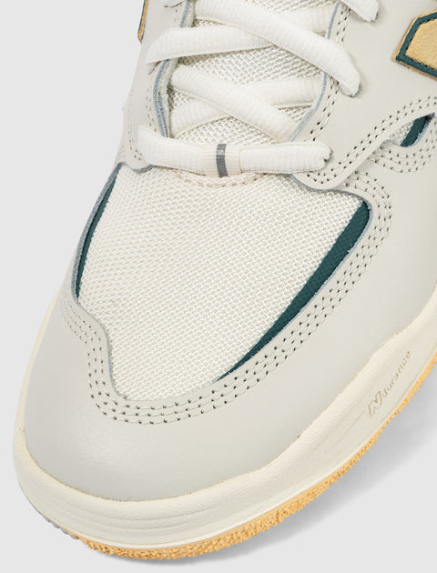 Close-up of white sneaker toe with mesh and suede details, rubber sole, and white laces.