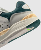 Close-up of a modern sneaker with green, beige, and off-white color blocking, textured sole.