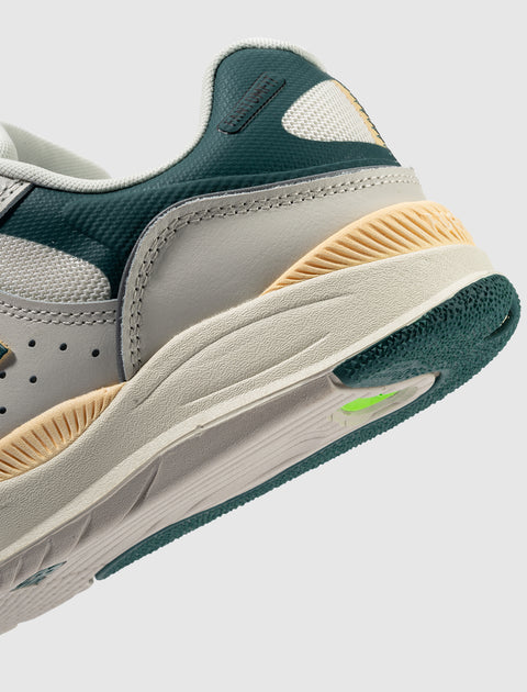 Close-up of a modern sneaker with green, beige, and off-white color blocking, textured sole.