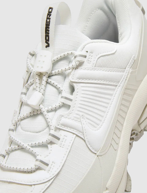 Close-up of a white athletic sneaker with unique lacing and VOMERO text on pull tab