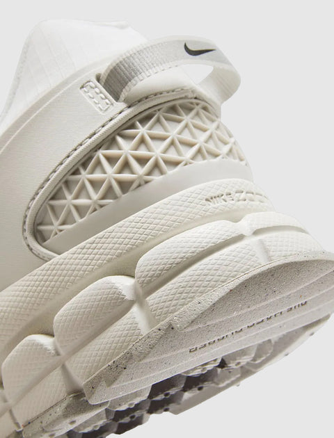 Close-up of white athletic sneaker heel with mesh details, textured sole, and Nike logo