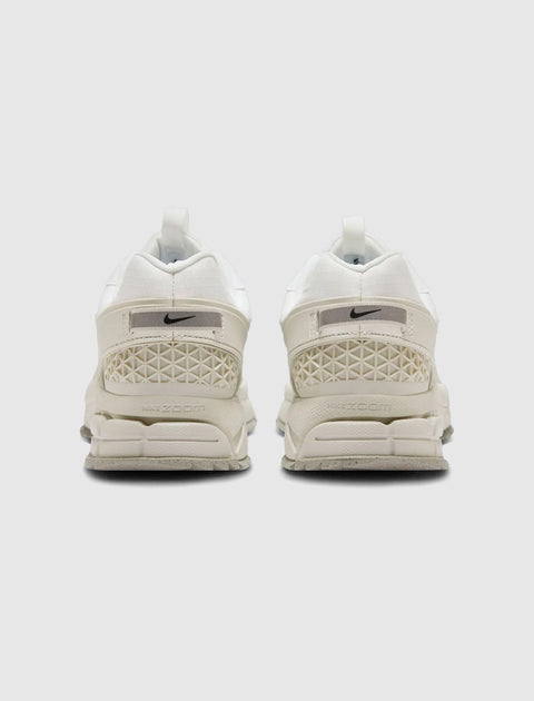 Rear view of white Nike Zoom sneakers with textured heel and light grey outsole on white background